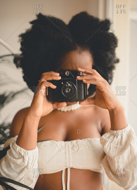Unrecognizable African American female photographer taking shots with vintage instant photo camera