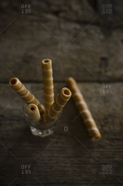 From above of tasty crispy striped waffle sticks placed in glass served on wooden table in kitchen