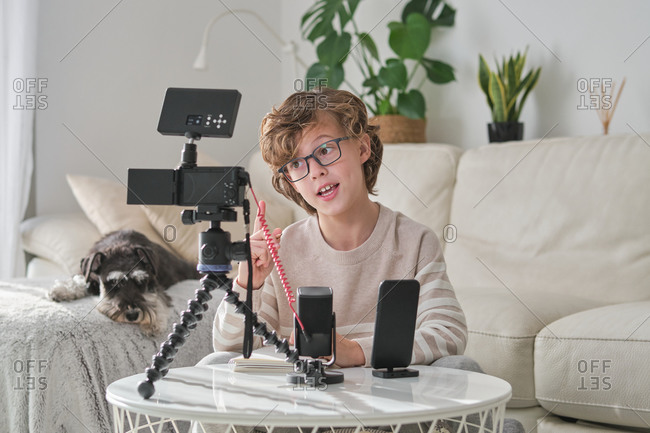 Cheerful young youtuber preteen boy filming video at home.