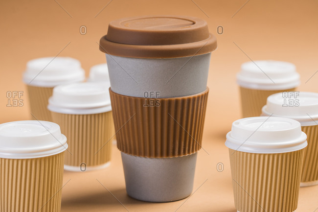 Various disposable cups of hot drinks placed on wooden table in cafe