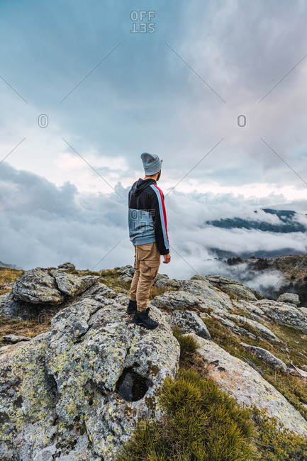 Back view of male hiker standing on top of hill and enjoying freedom in highlands during adventure