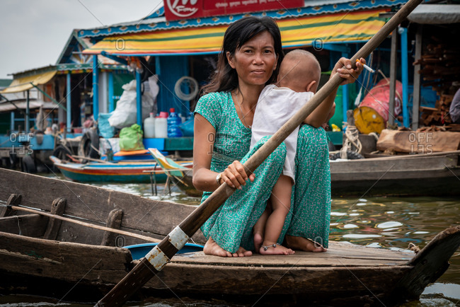 Kompong Luong Floating Village, Krakor District, Cambodia - 15 April 2012: Mother Rows Through Cambodian Floating Village With Baby And Cigarette.
