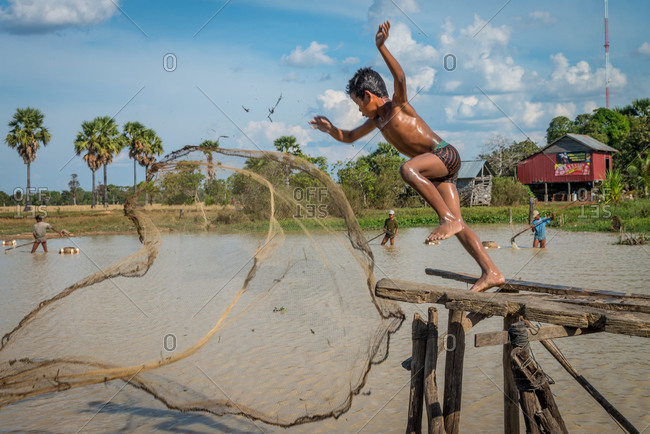 Throwing Fishing Net, Kompong Thom, Cambodia - 10 January 2013: Young Khmer Throws His Fishing Net So Hard He Falls In Water.