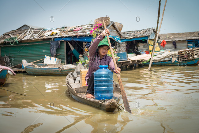 Floating Village, Kompong Chnang, Cambodia - 20 March 2013: Khmer Woman Rows Through Floating Village Delivering Fresh Water.
