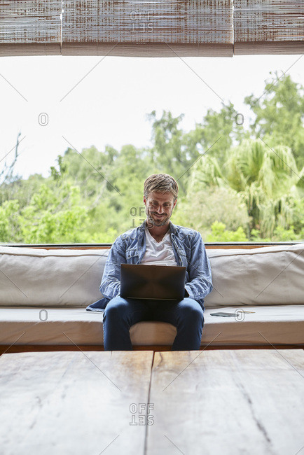 Smiling mid adult man using laptop