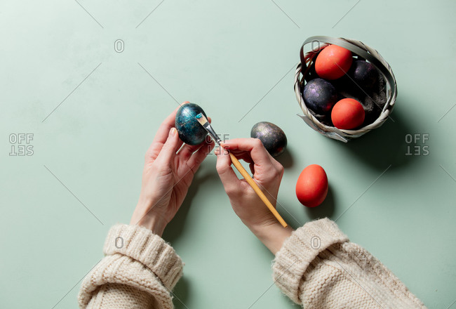 Female brushing an easter eggs on turquoise background