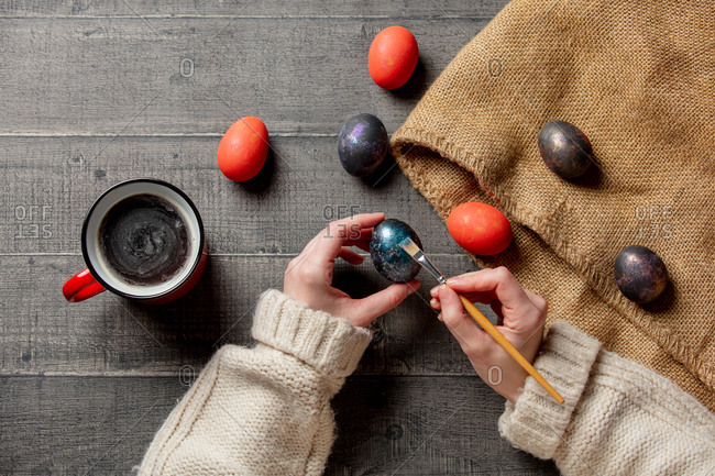 Female brushing an easter eggs and drink a coffee