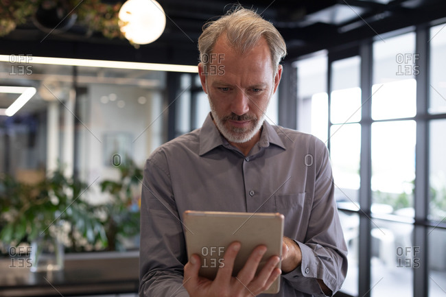 Caucasian businessman standing by window using digital tablet in modern office. business modern office workplace technology.