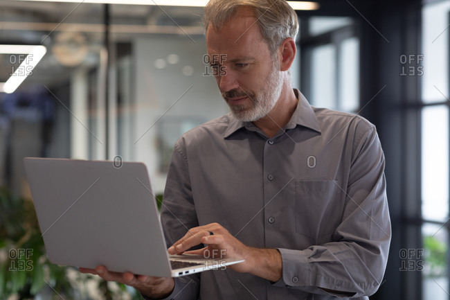 Caucasian businessman standing by window using laptop in modern office. business modern office workplace technology.