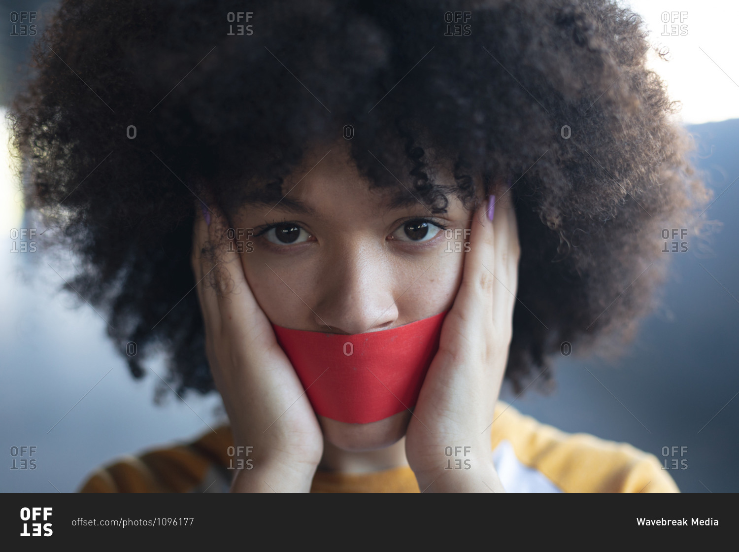 Mixed race woman with tape on mouth looking at camera. gender fluid lgbt identity racial equality concept.
