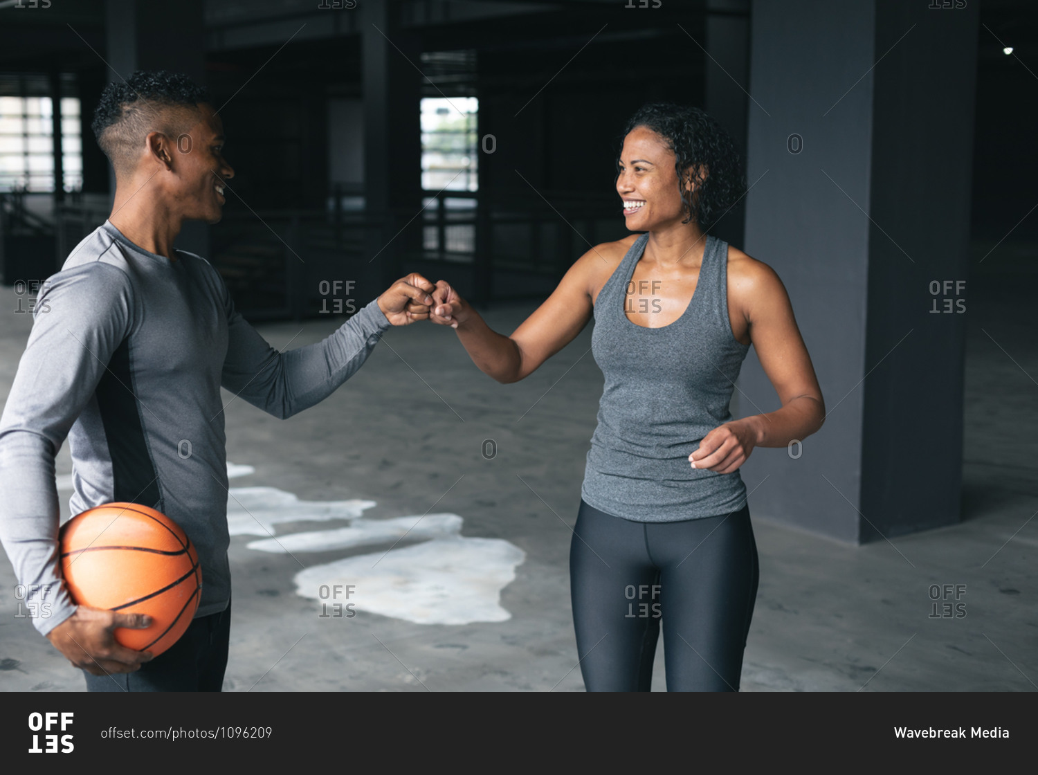 African American man and woman standing in an empty urban building and fist bumping. urban fitness healthy lifestyle.