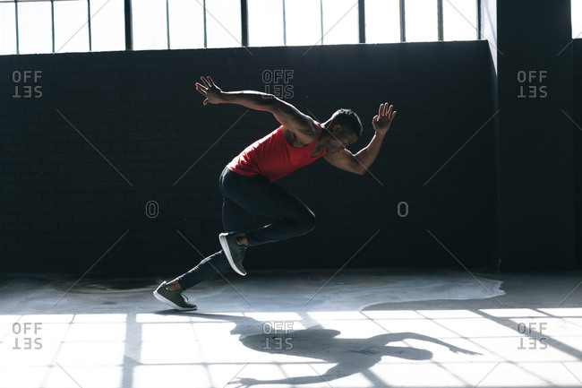 African American man wearing sports clothes sprinting in empty urban building. urban fitness healthy lifestyle.