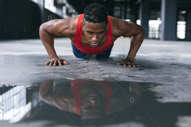 African American man wearing sports clothes doing push ups in empty urban building. urban fitness healthy lifestyle.