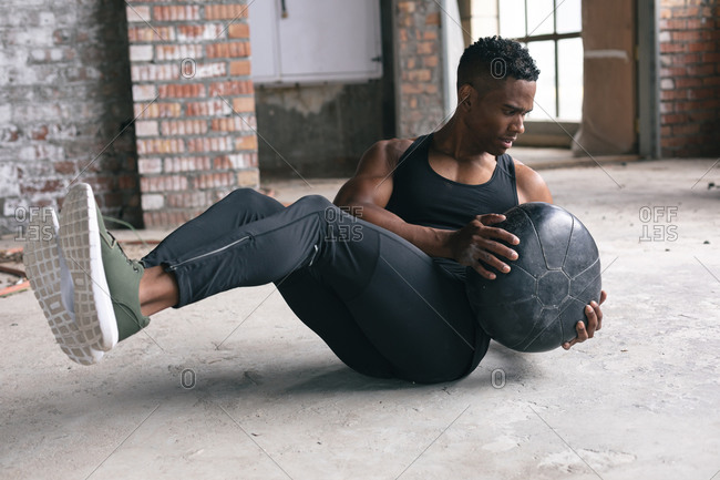 African American man exercising with a medicine ball in empty urban building. urban fitness healthy lifestyle.