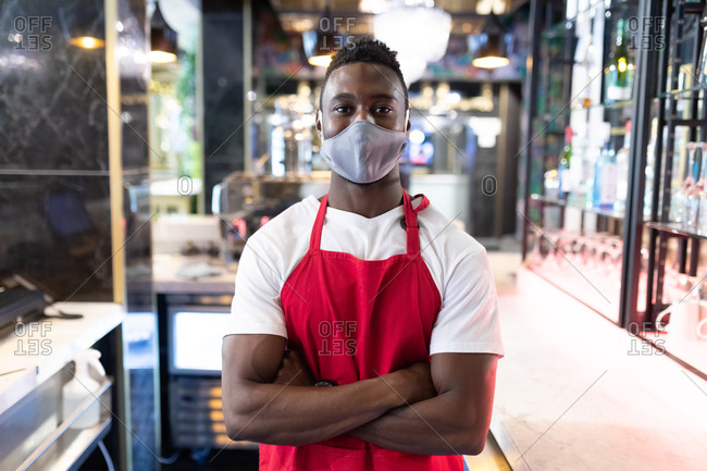 Portrait of African American male barista wearing face mask looking at the camera. health and hygiene in business during coronavirus covid 19 pandemic.