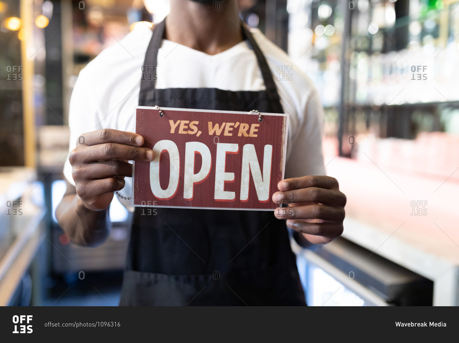 Portrait of African American male barista holding a were open card. independent small business owner.