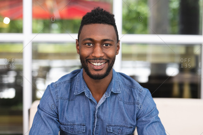 Portrait of African American man sitting in a cafe looking at camera and smiling. businessman on the go out in the city.
