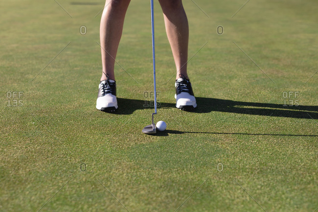 Low section of caucasian woman putting ball with club on golf course. sport leisure hobbies golf healthy outdoor lifestyle.