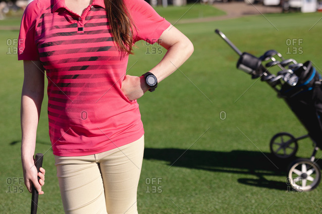 Midsection of caucasian woman standing on golf course holding golf club. sport leisure hobbies golf healthy outdoor lifestyle.