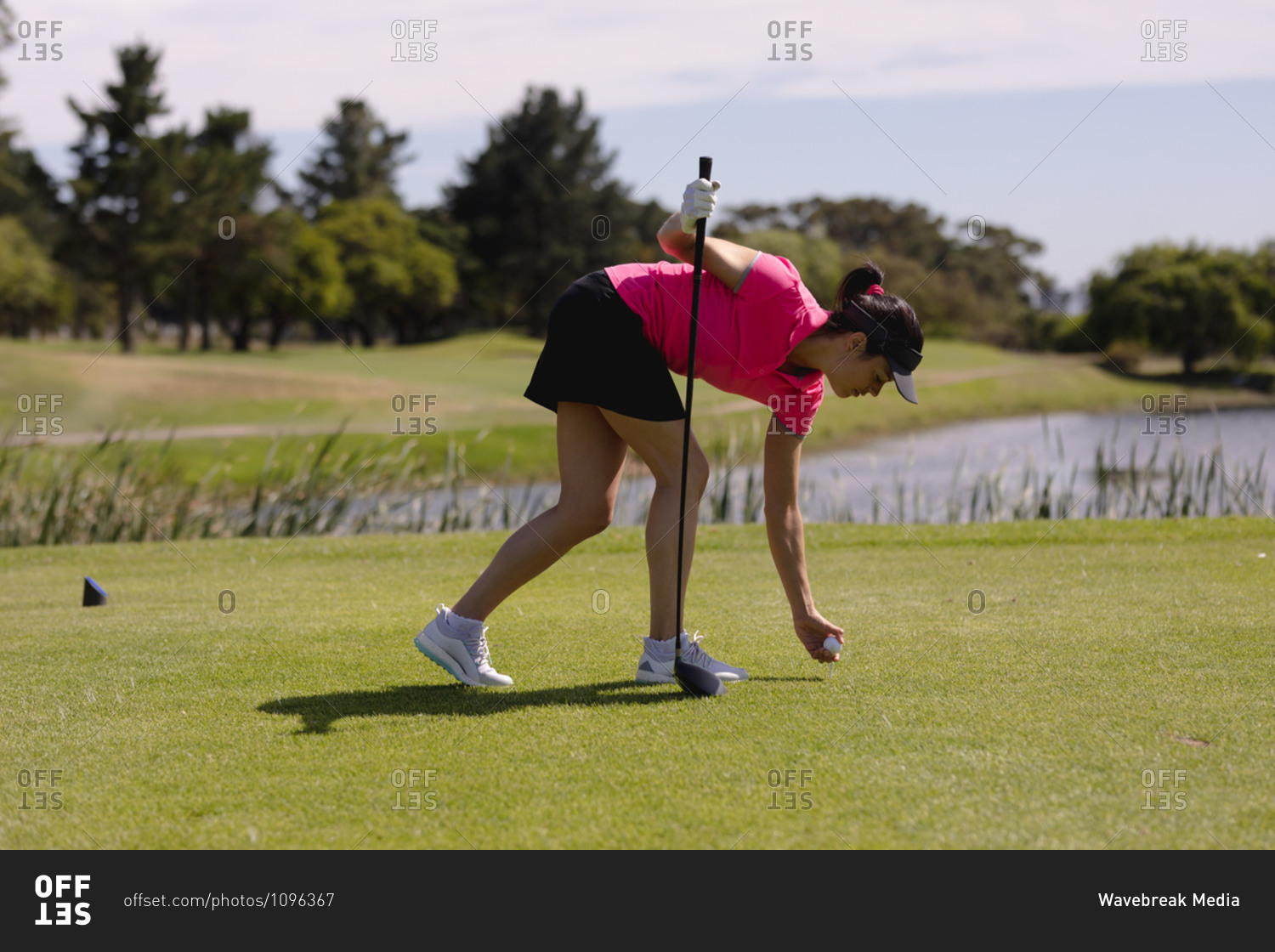 Caucasian woman playing golf leaning to place ball before taking a shot. sport leisure hobbies golf healthy outdoor lifestyle.