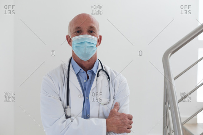 Portrait of senior caucasian male doctor wearing a face mask looking at the camera. healthcare hygiene protection during coronavirus covid 19 pandemic.
