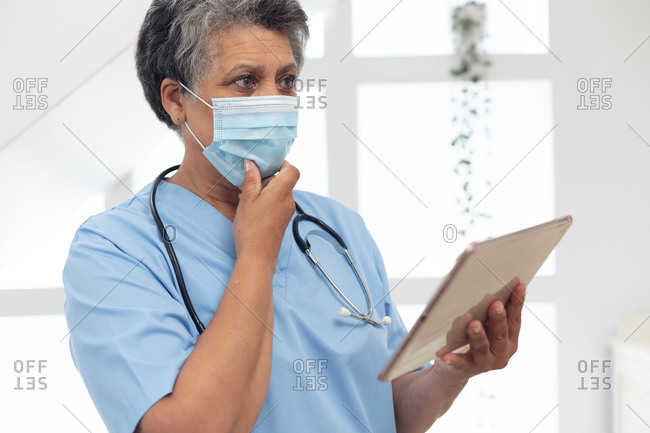 Senior African American female doctor wearing a face mask using a digital tablet. healthcare hygiene protection during coronavirus covid 19 pandemic.