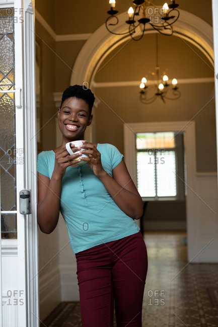Portrait of African American woman holding coffee cup smiling at home. staying at home in self isolation in quarantine lockdown