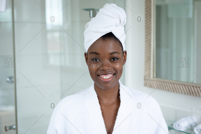 Portrait of African American woman in bathrobe smiling in bathroom at home. staying at home in self isolation in quarantine lockdown