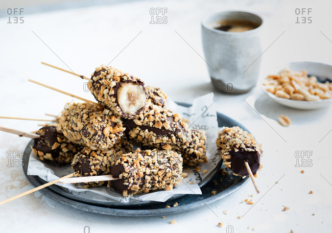 Bananas dipped in chocolate and nuts frozen dessert cup of coffee