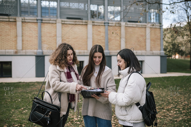 Three college students sharing notes on campus