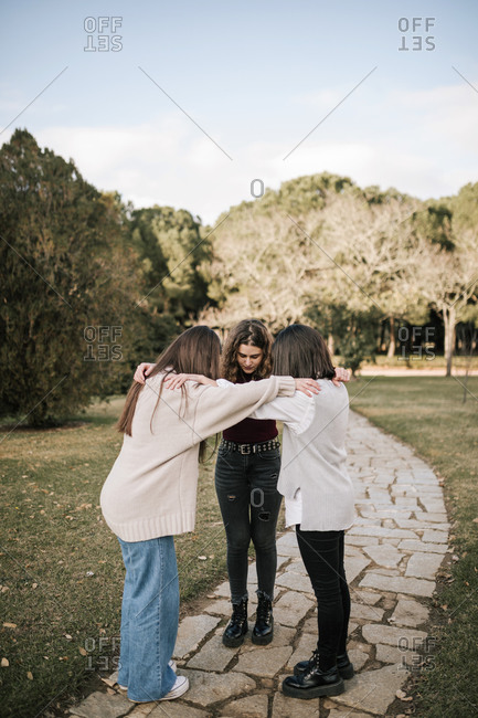 Three Caucasian female friends hugging on a college campus