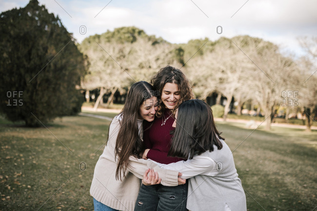 Three Caucasian female friends hugging on a college campus