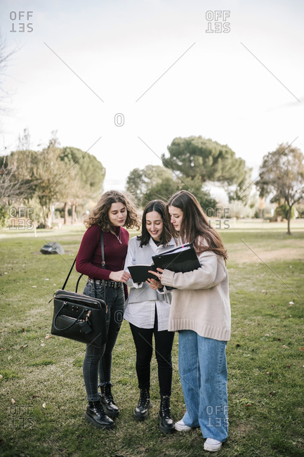 Three college students sharing notes on campus