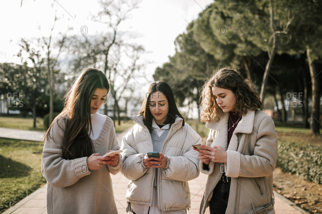 Three young women looking at a cell phone each on a college campus