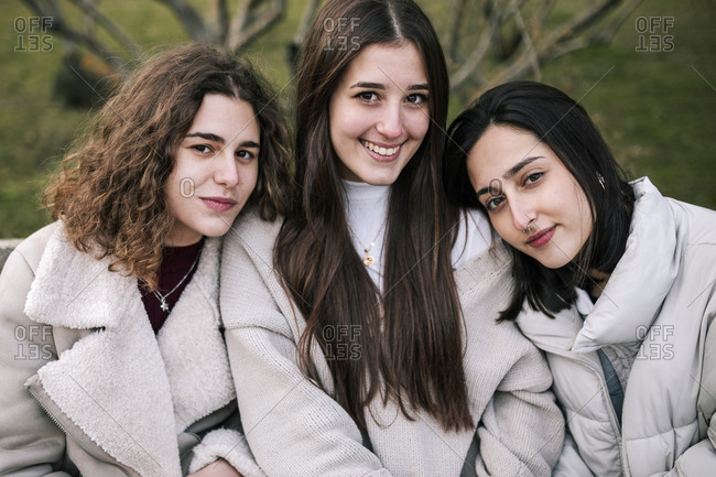 Portrait of three young Caucasian women sitting on a park bench in winter