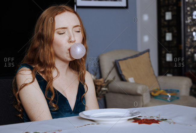 Staying at home teenage girl blowing bubbles with bubblegum