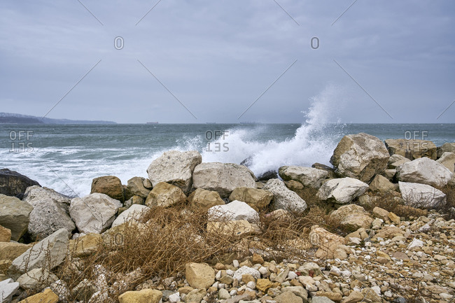 sea with big waves crashing to shore and rocks