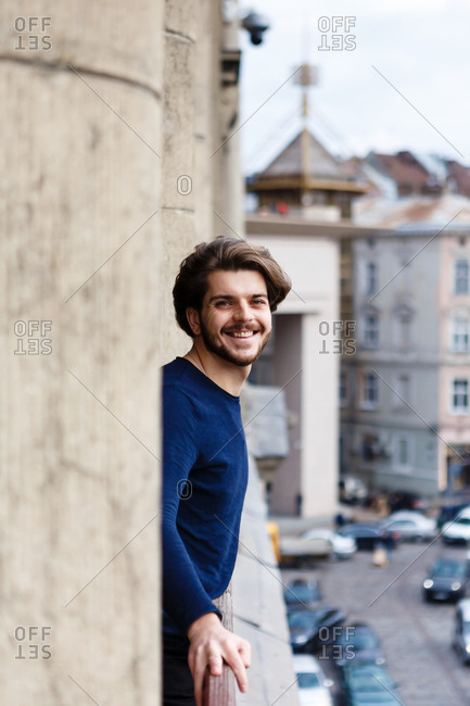 Young man with a beard and beautiful hair on the balcony alone