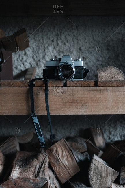 Film camera over a wooden shelf full of firewood