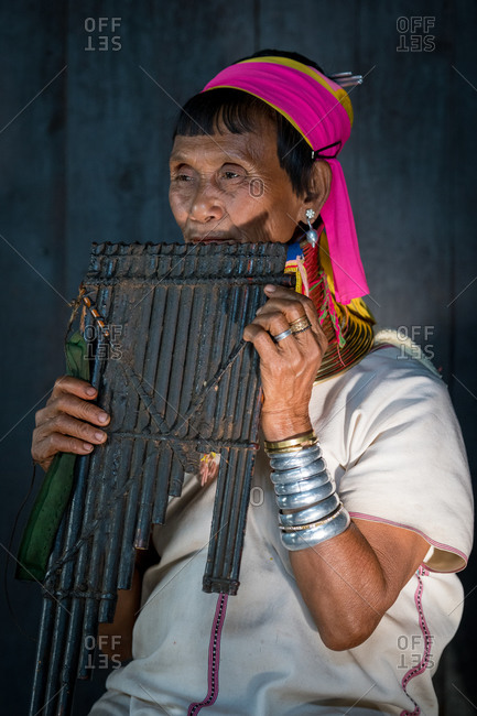 PADUANG PEOPLE, PAN PET VILLAGE, KAYAH STATE, MYANMAR - 28 January 2019: Portrait of local lady wearing brass coils placed around the neck, appearing to lengthen it. playing musical instrument.