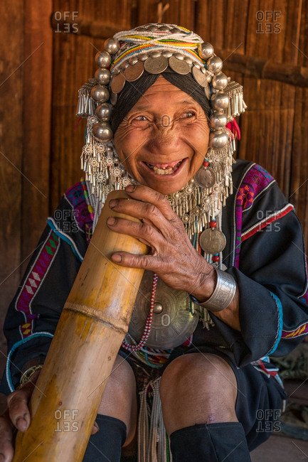 AKHA HILL TRIBE, HOKYIN VILLAGE, MYANMAR - 19 November 2019: Woman in traditional costume smokes bamboo water pipe.