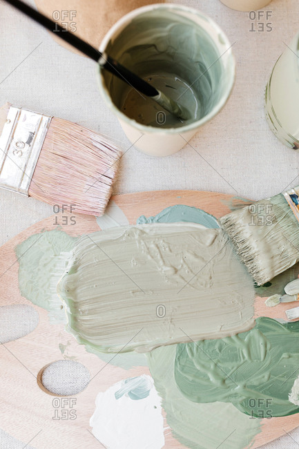 From above of paint palette with pastel pigments placed on table with brushes in art studio