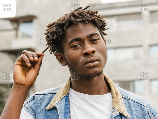 Confident black and white of serious young African American hipster male with Afro hairstyle looking at camera