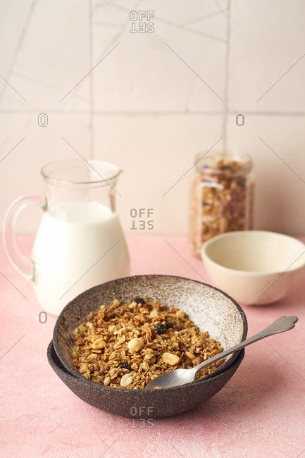 A bowl of granola with nuts, honey and oats served with milk