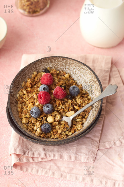 A bowl of granola with nuts and oats served with berries and milk