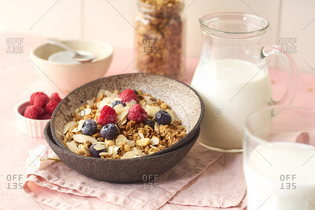 A bowl of granola with nuts and oats served with berries and milk
