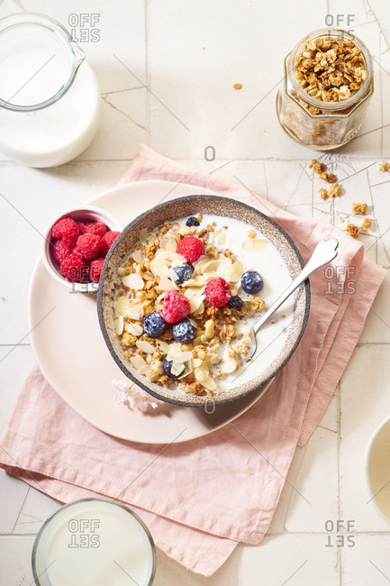 Flat lay with a bowl of granola with nuts and oats served with berries and milk