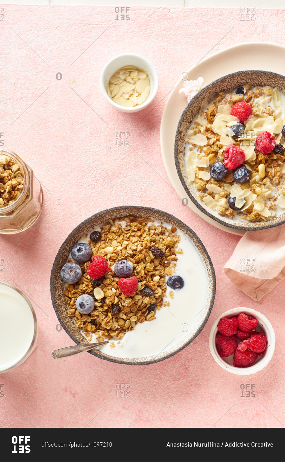 Top view of tasty breakfast with granola, berries and milk on pink background
