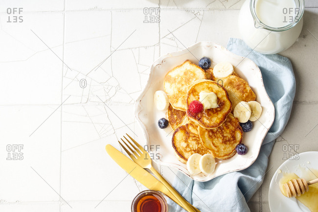 Top view of a plate with fluffy breakfast pancakes with maple syrup and berries