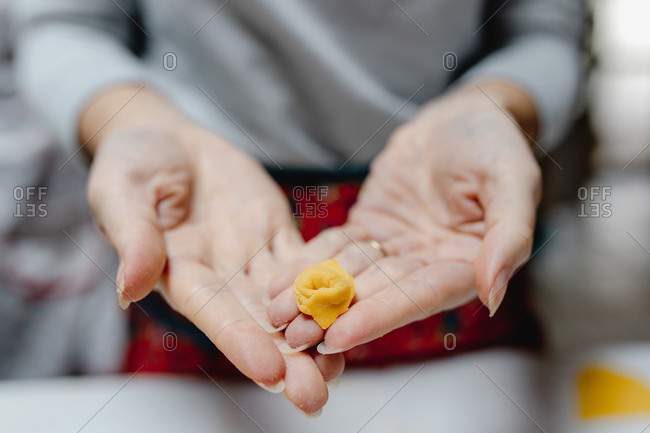 High angle of crop anonymous female standing with traditional Italian tortellini in kitchen at home